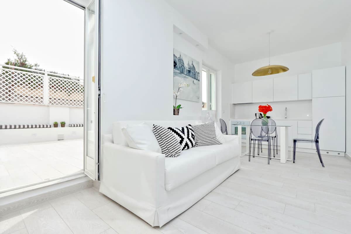 A modern, white interior with a sofa, dining area, and kitchen.