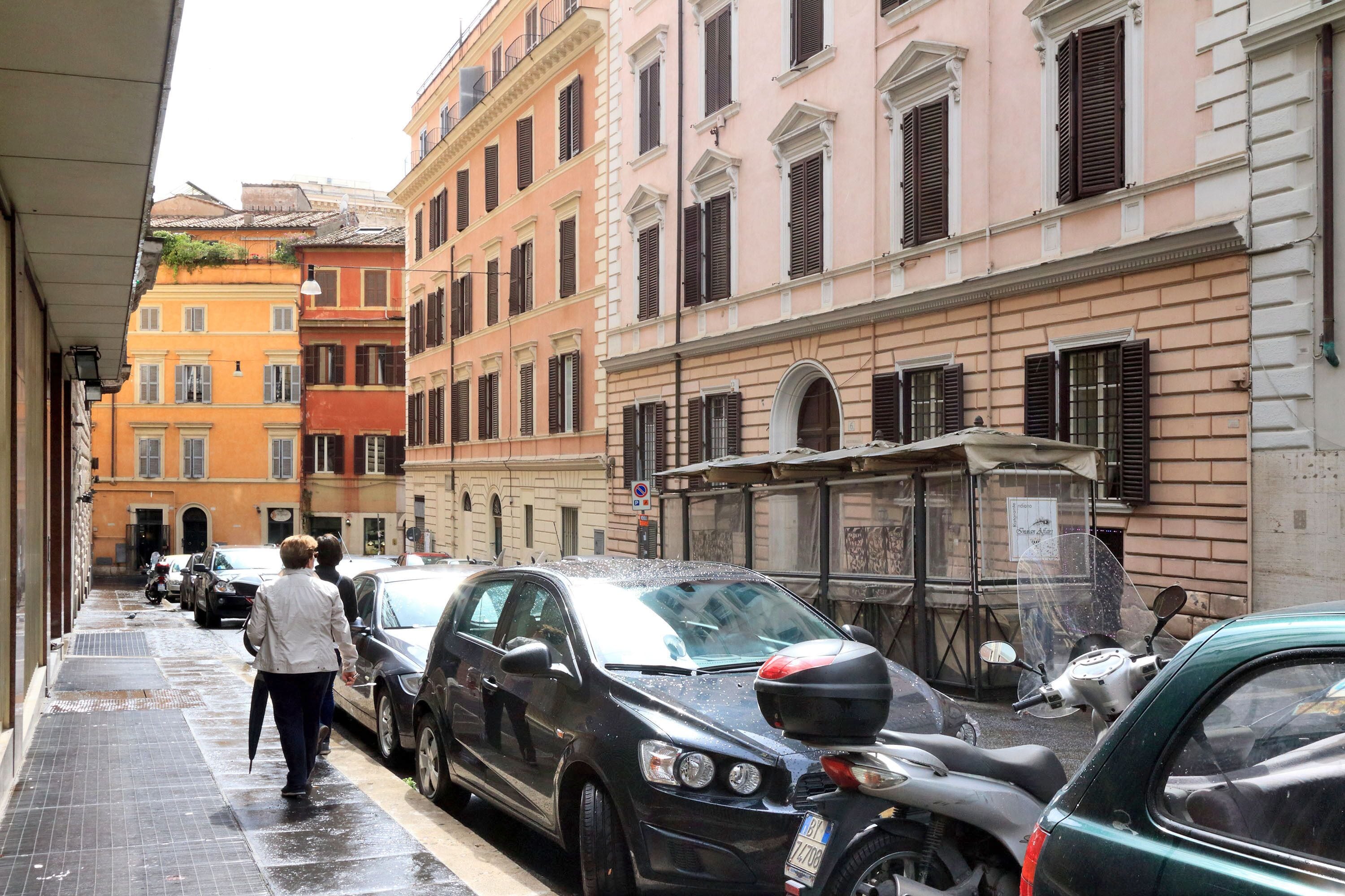 A narrow street lined with parked cars and buildings with classic architecture.