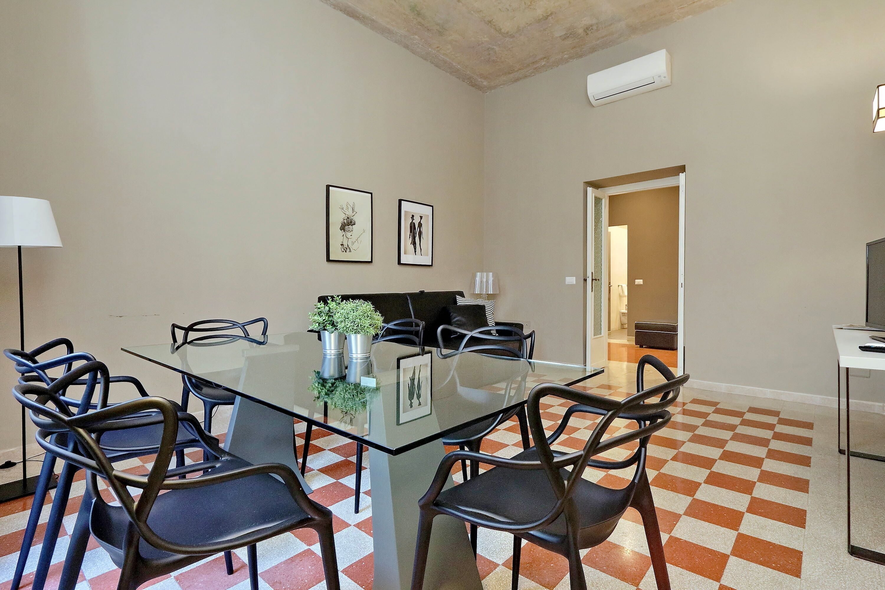 A conference room with a glass table, black chairs, and framed artwork on the walls.