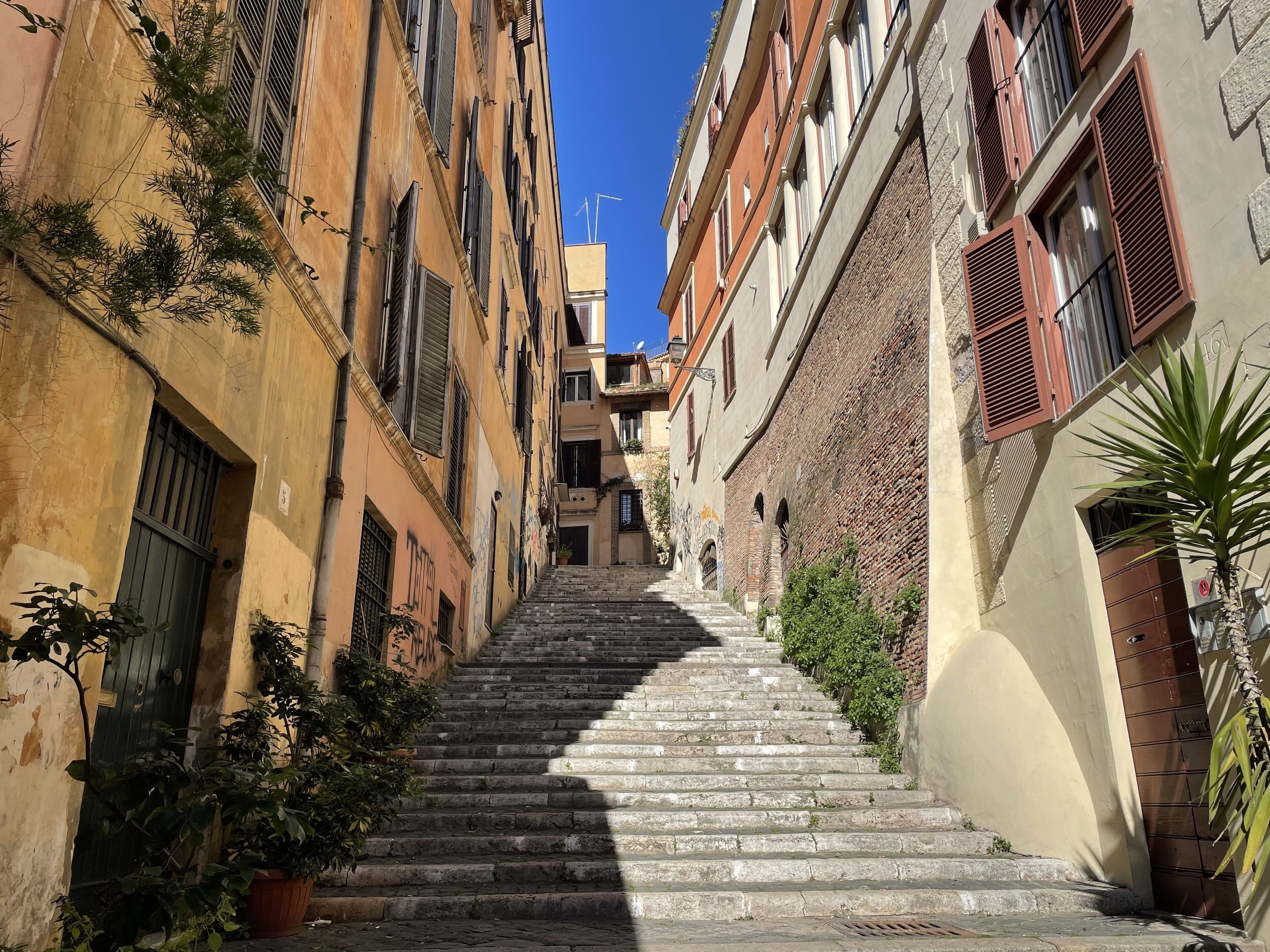 Une rue étroite, avec des marches en pierre menant à un immeuble doté de nombreuses fenêtres et de balcons.