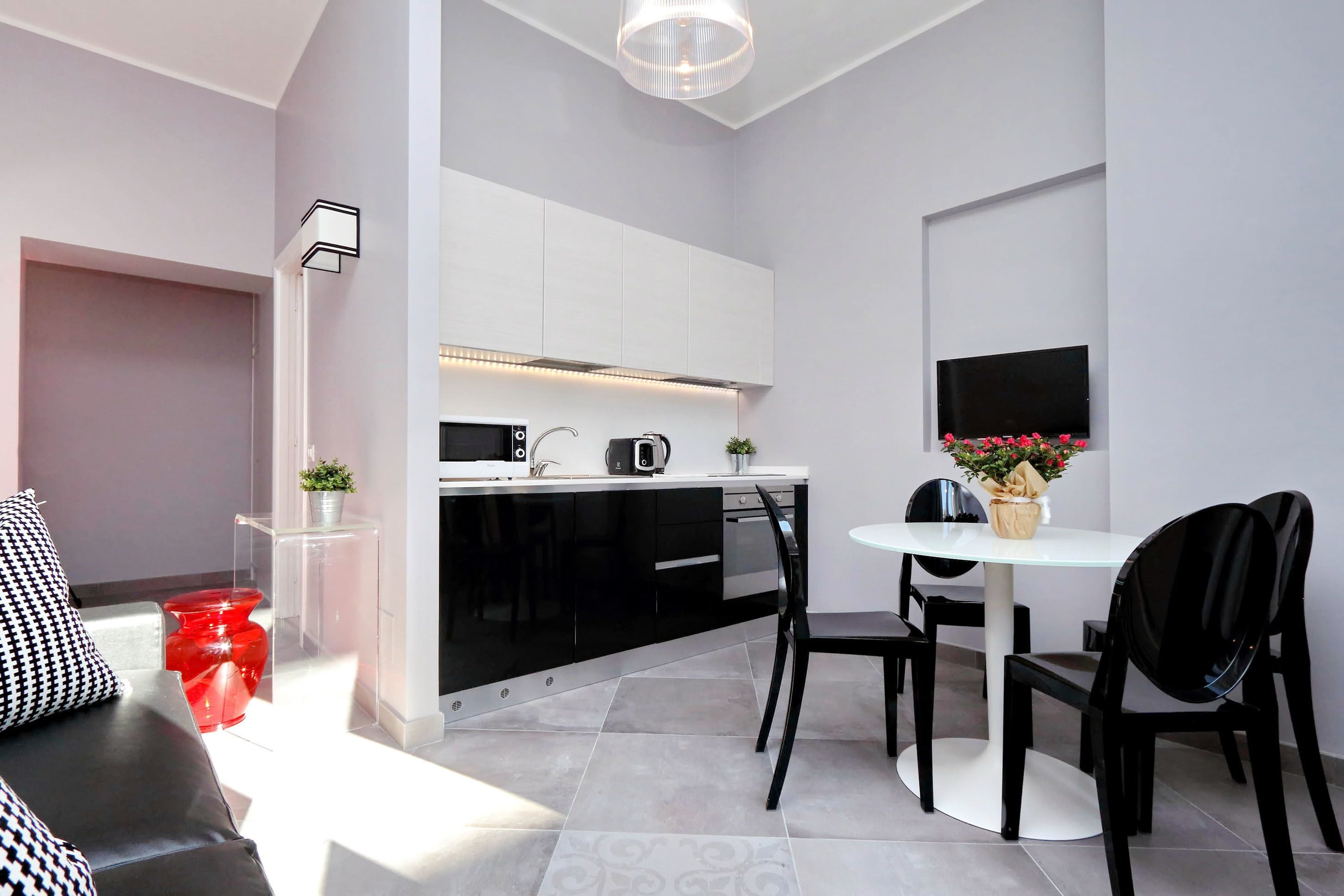 A modern kitchen with white cabinets, a black countertop, and a dining area with a round table and black chairs.