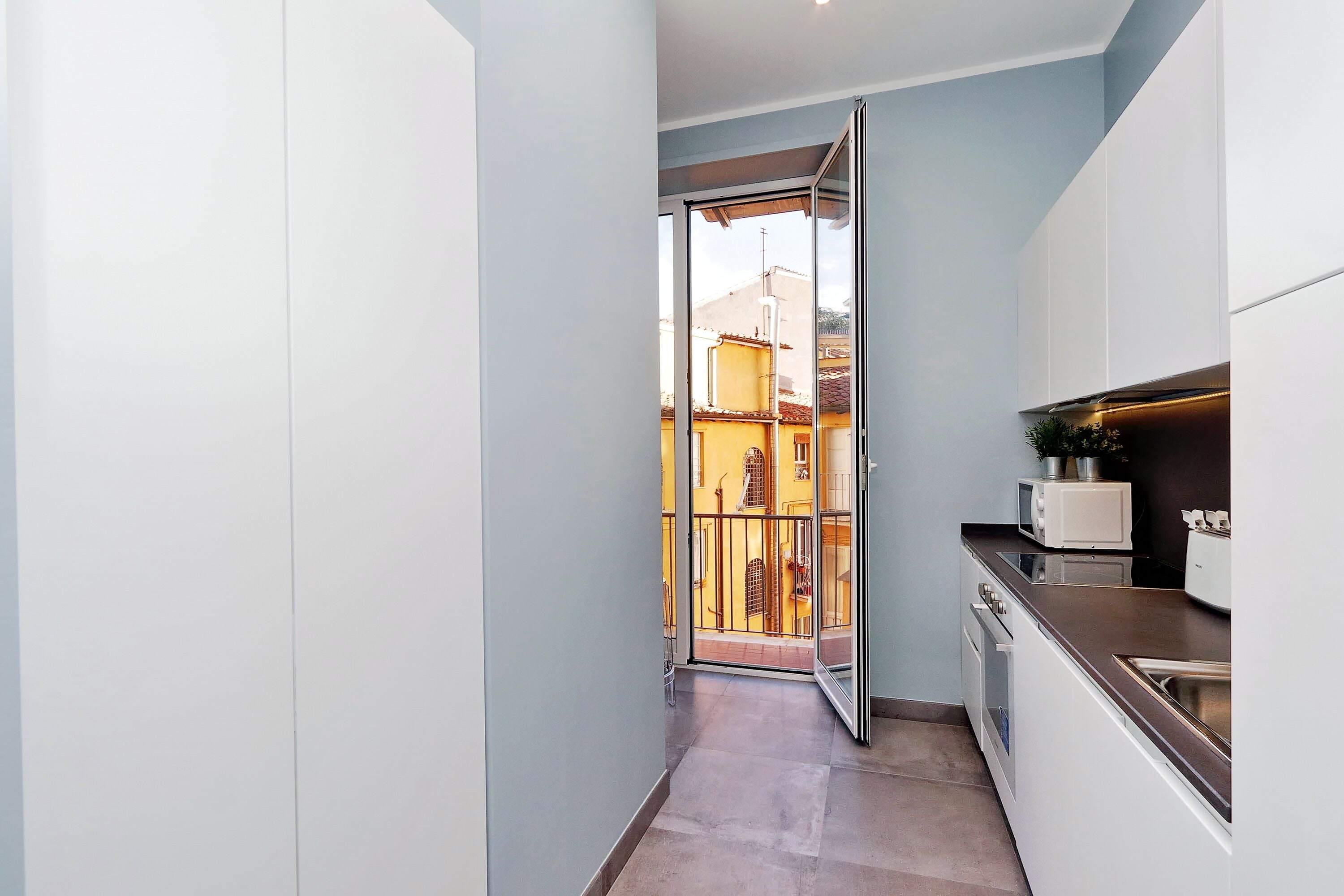Une cuisine étroite avec une porte-fenêtre coulissante donnant sur un balcon.