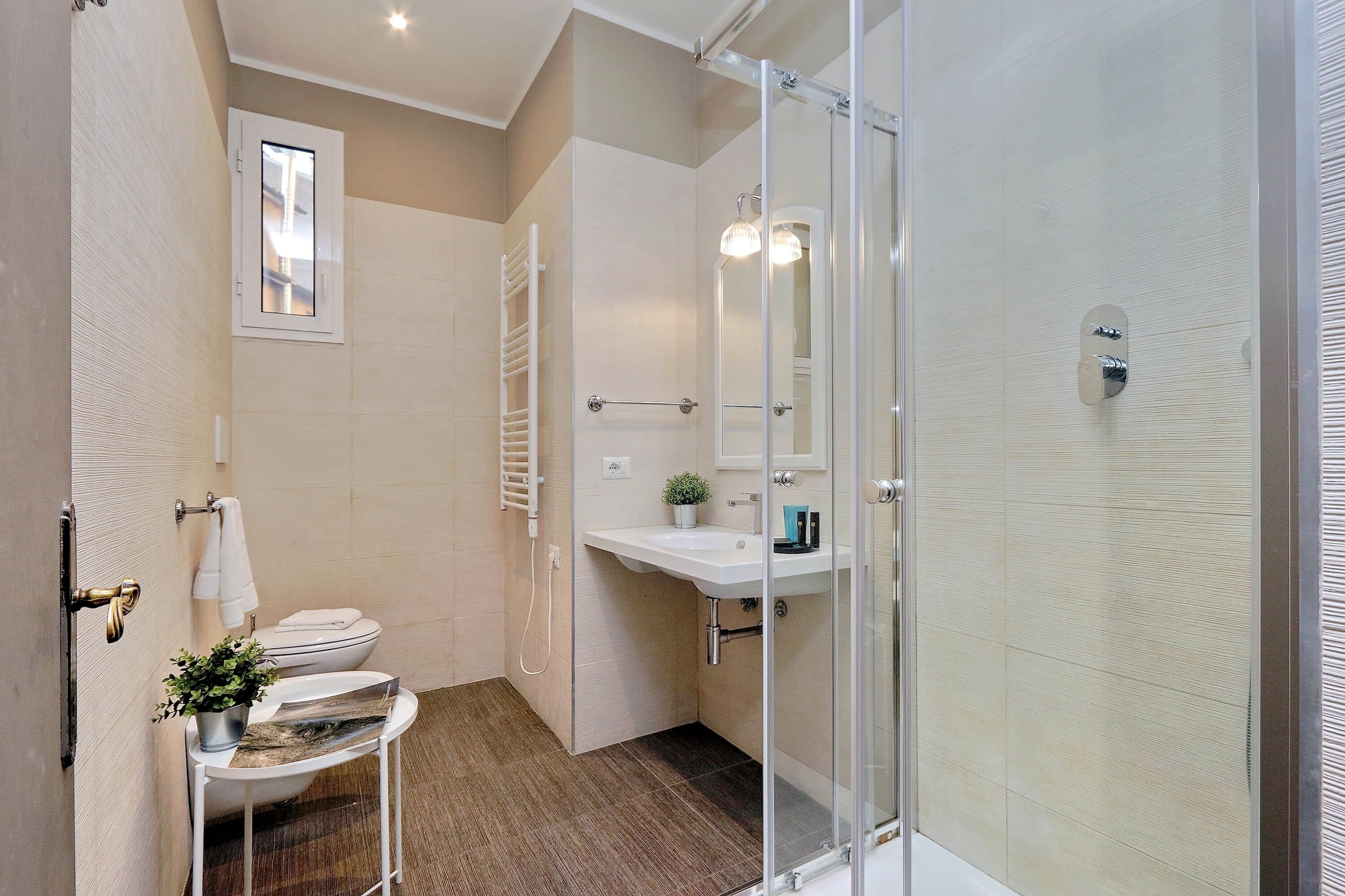 A modern bathroom with a glass shower enclosure, a white sink, and a toilet.