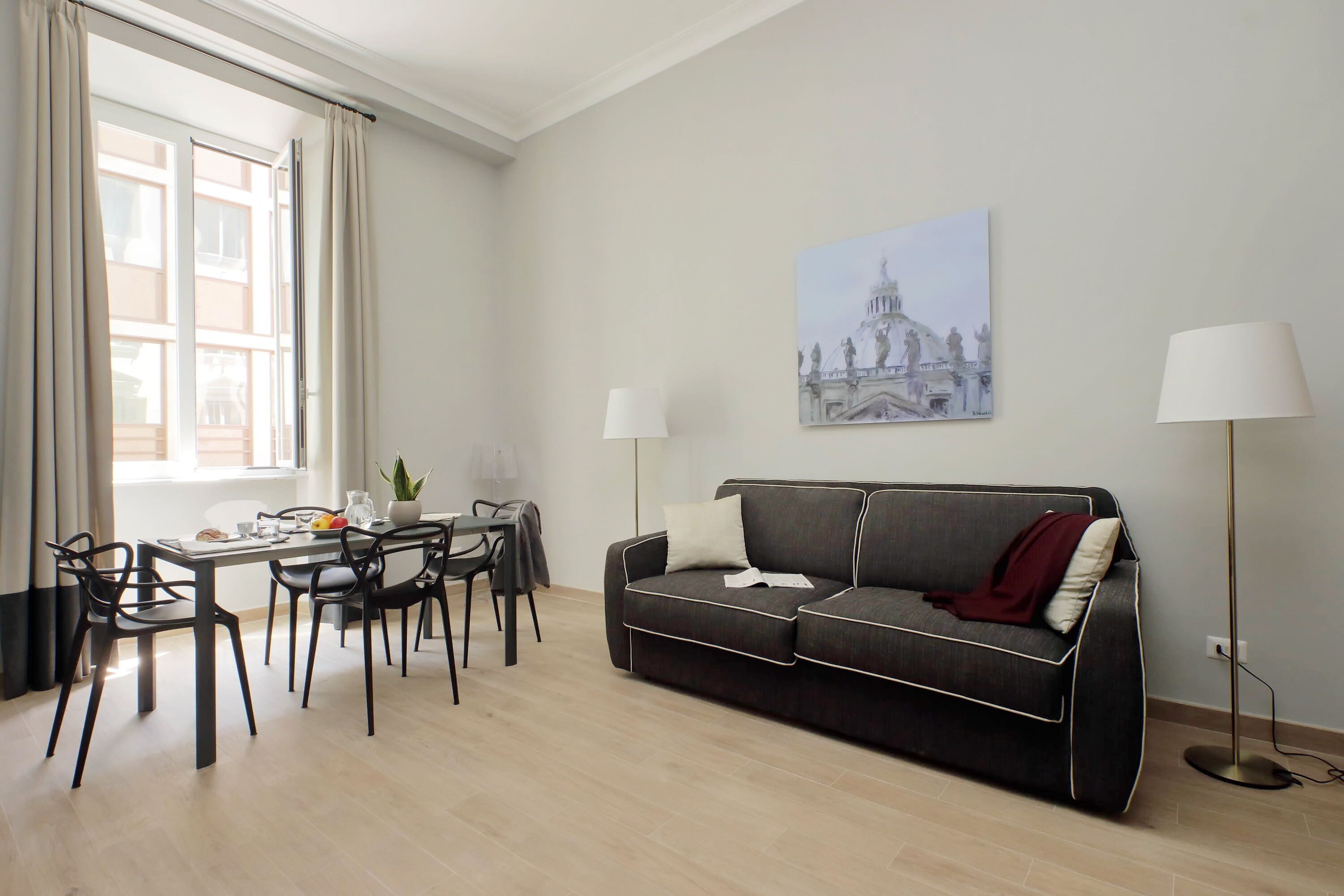A modern living room with a sofa, dining table, chairs, and a lamp.