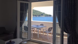Een kamer met een balkon, een tafel en stoelen.