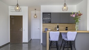 Een moderne keuken met twee barkrukken, een houten aanrechtblad en hanglampen.