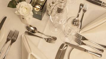 A table set for a formal dinner with silverware, plates, and clear glassware.