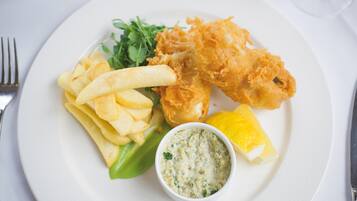 A plate with fried fish, chips, a lemon wedge, and a side salad.