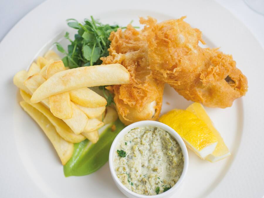 A plate with fried fish, chips, a lemon wedge, and a side salad.