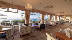 A spacious lounge with comfortable seating, large windows, and a view of the sea. - The Royal Duchy Hotel (Falmouth)