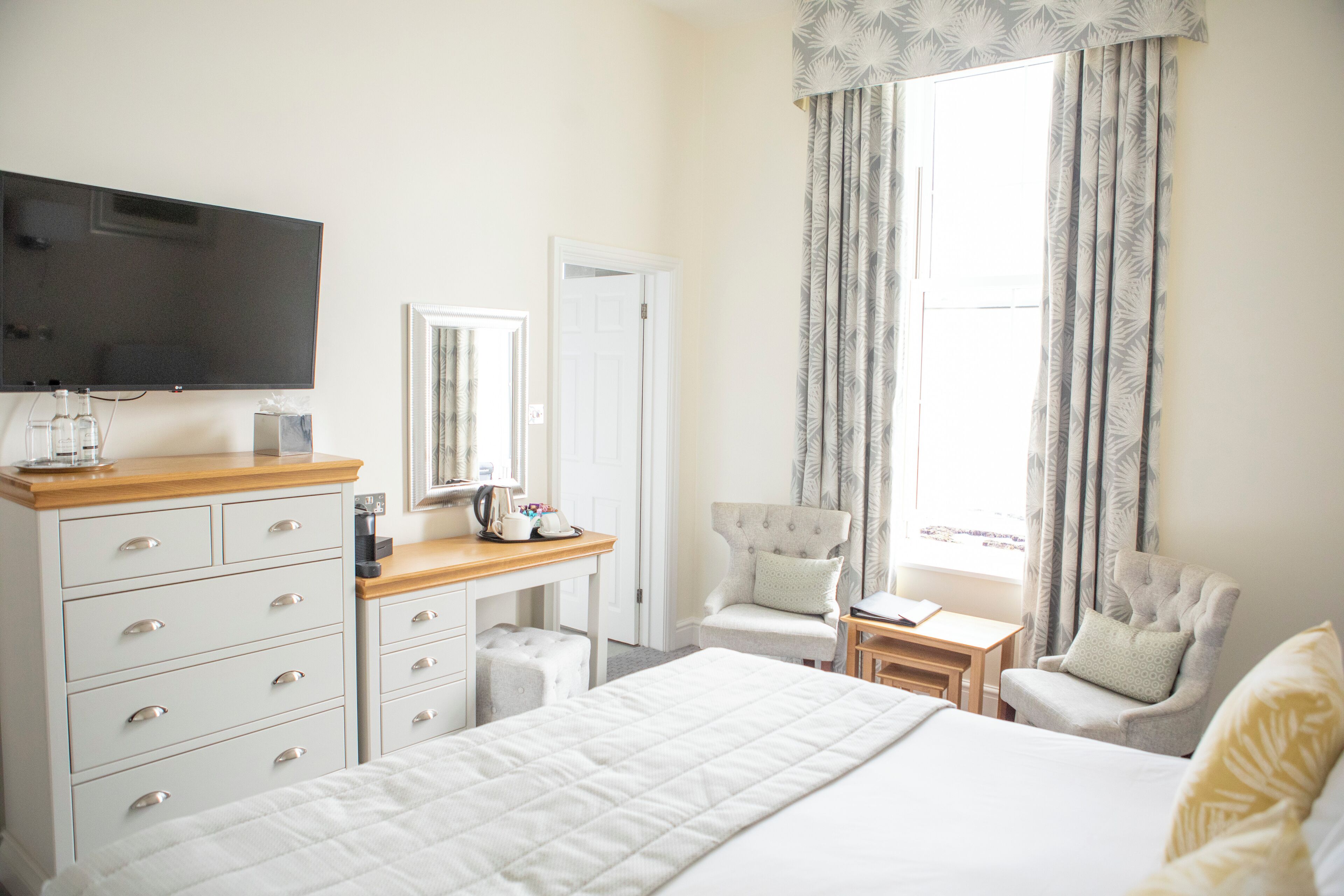 A hotel room with a bed, a desk, a chair, a television, and curtains.