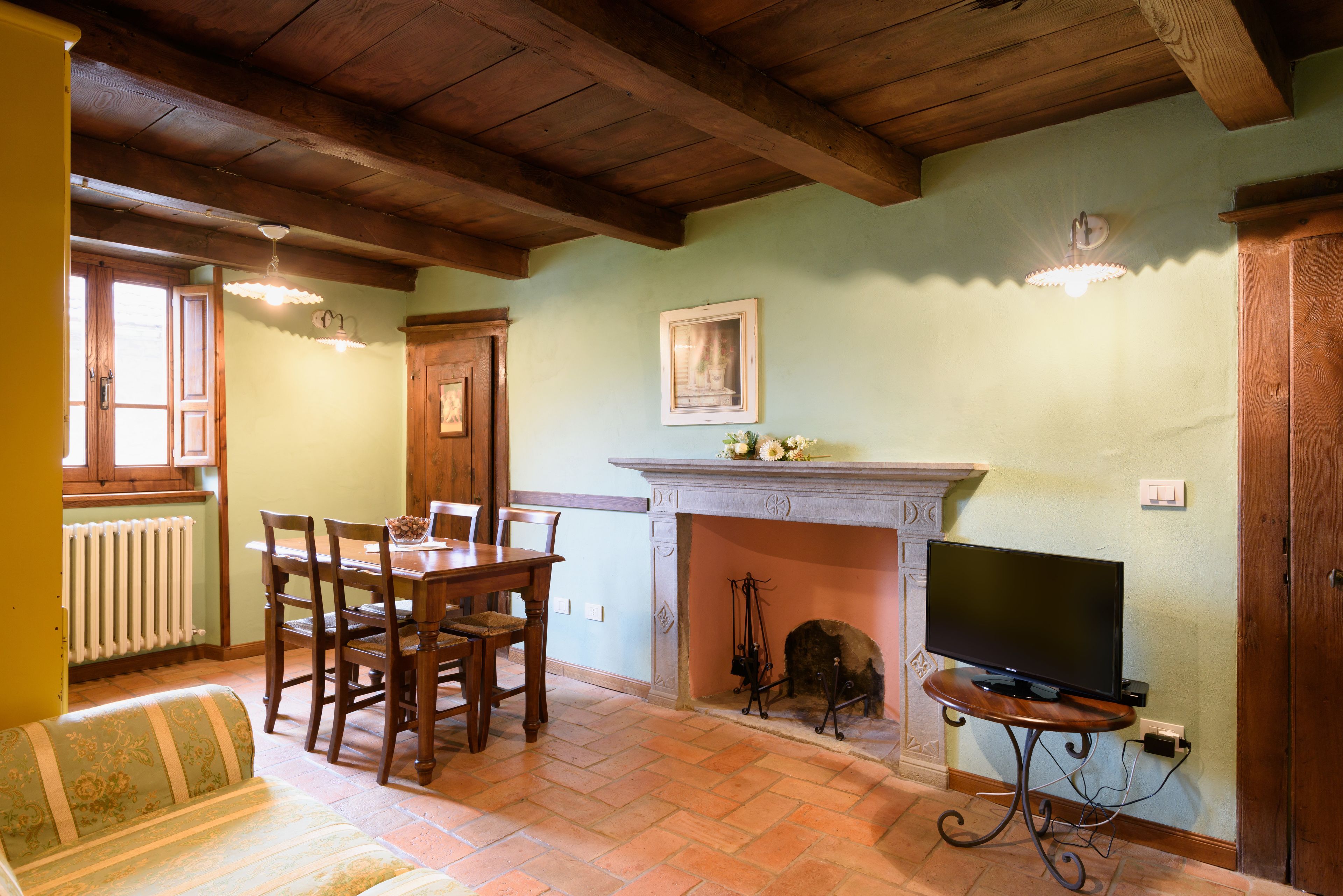 A dining area with a wooden table and chairs, a fireplace, and a television on a stand.