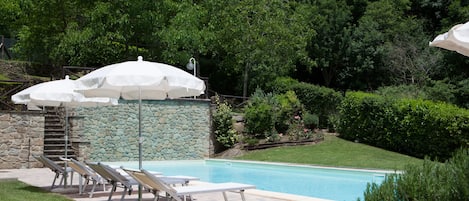 Una piscina al aire libre de temporada, sombrillas, tumbonas