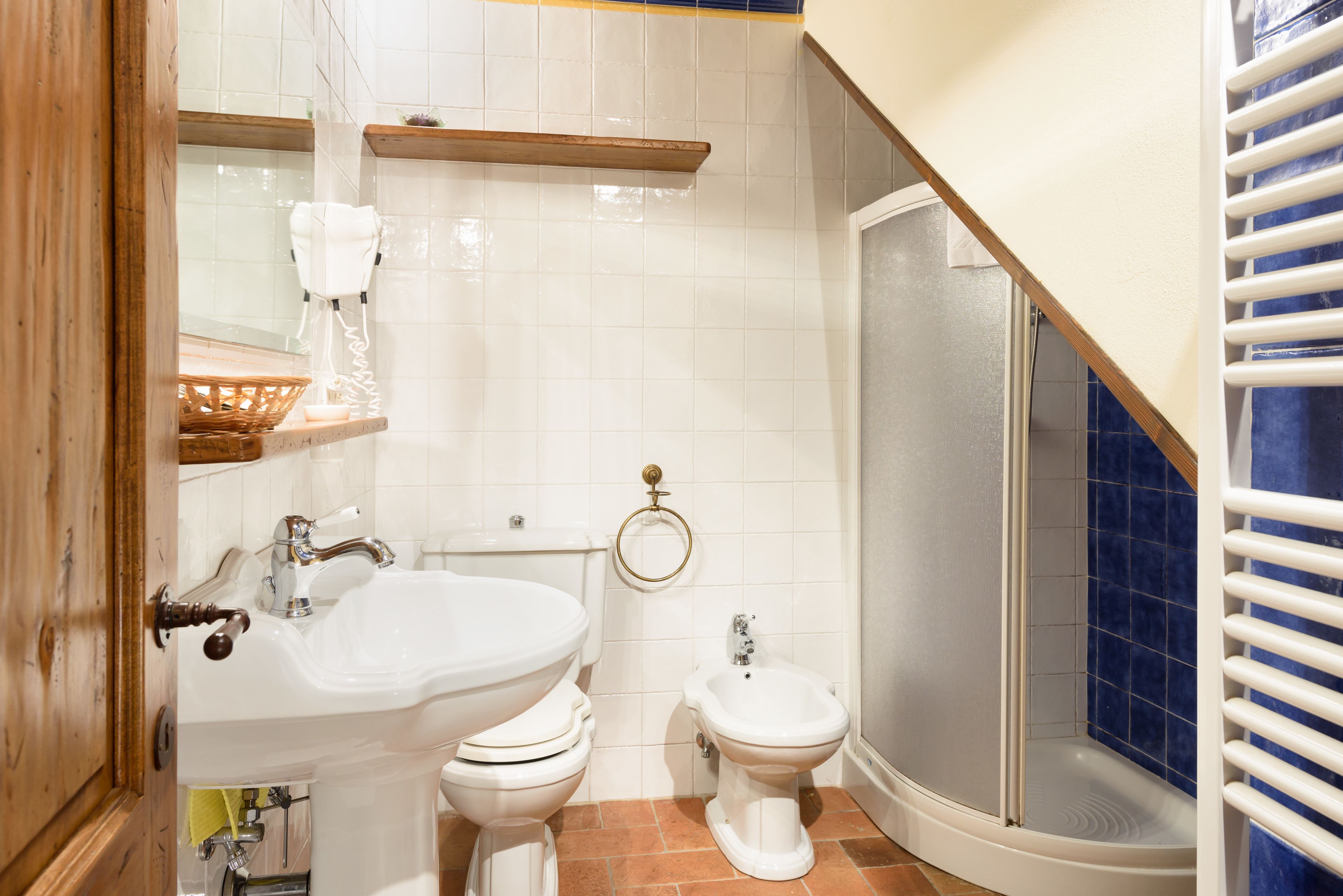 A bathroom with a sink, two toilets, a bidet, and a shower.