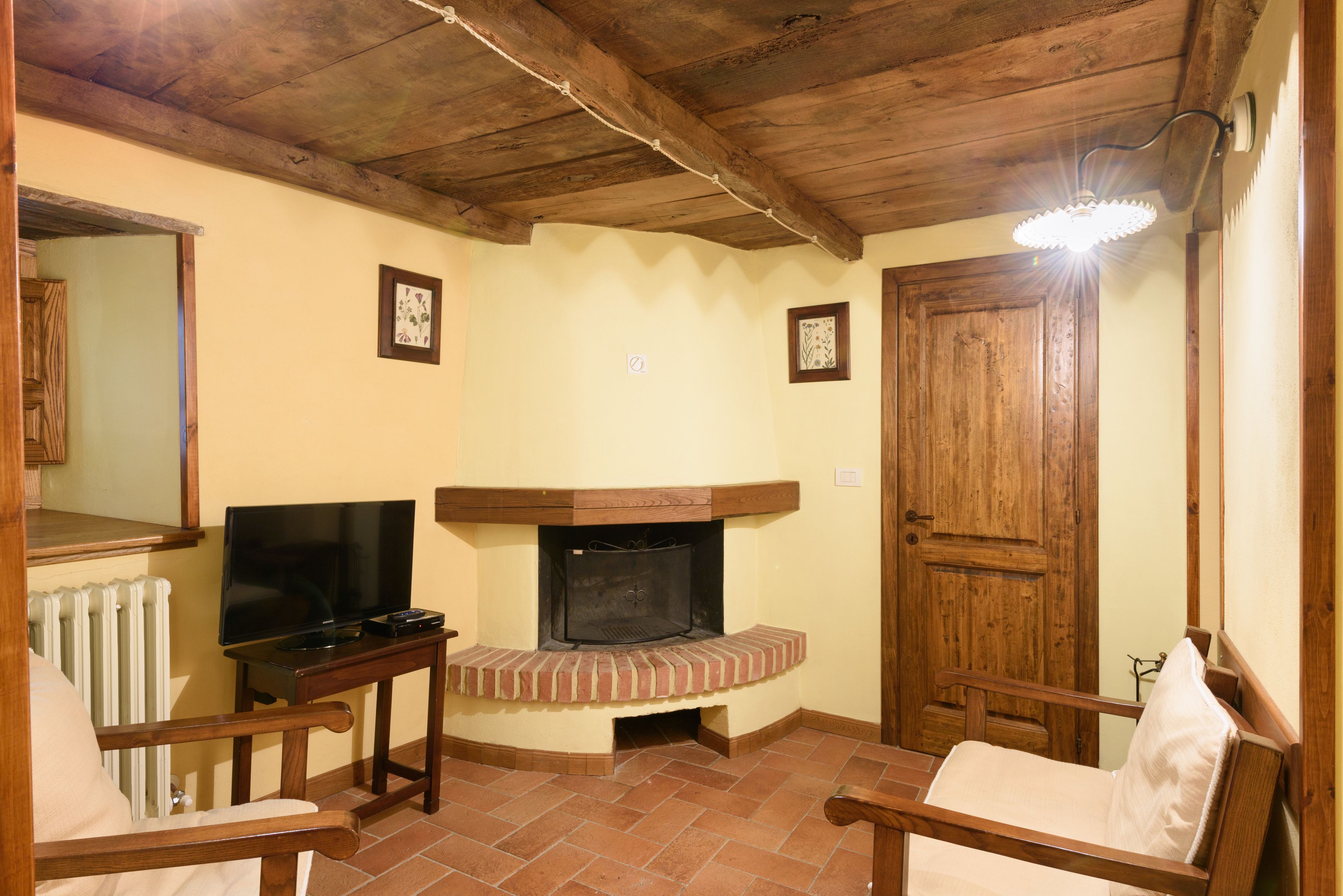 A cozy living room with a fireplace, wooden furniture, and a television.