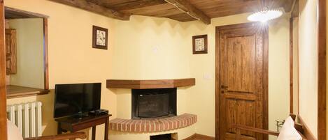 A cozy living room with a fireplace, wooden furniture, and a television.