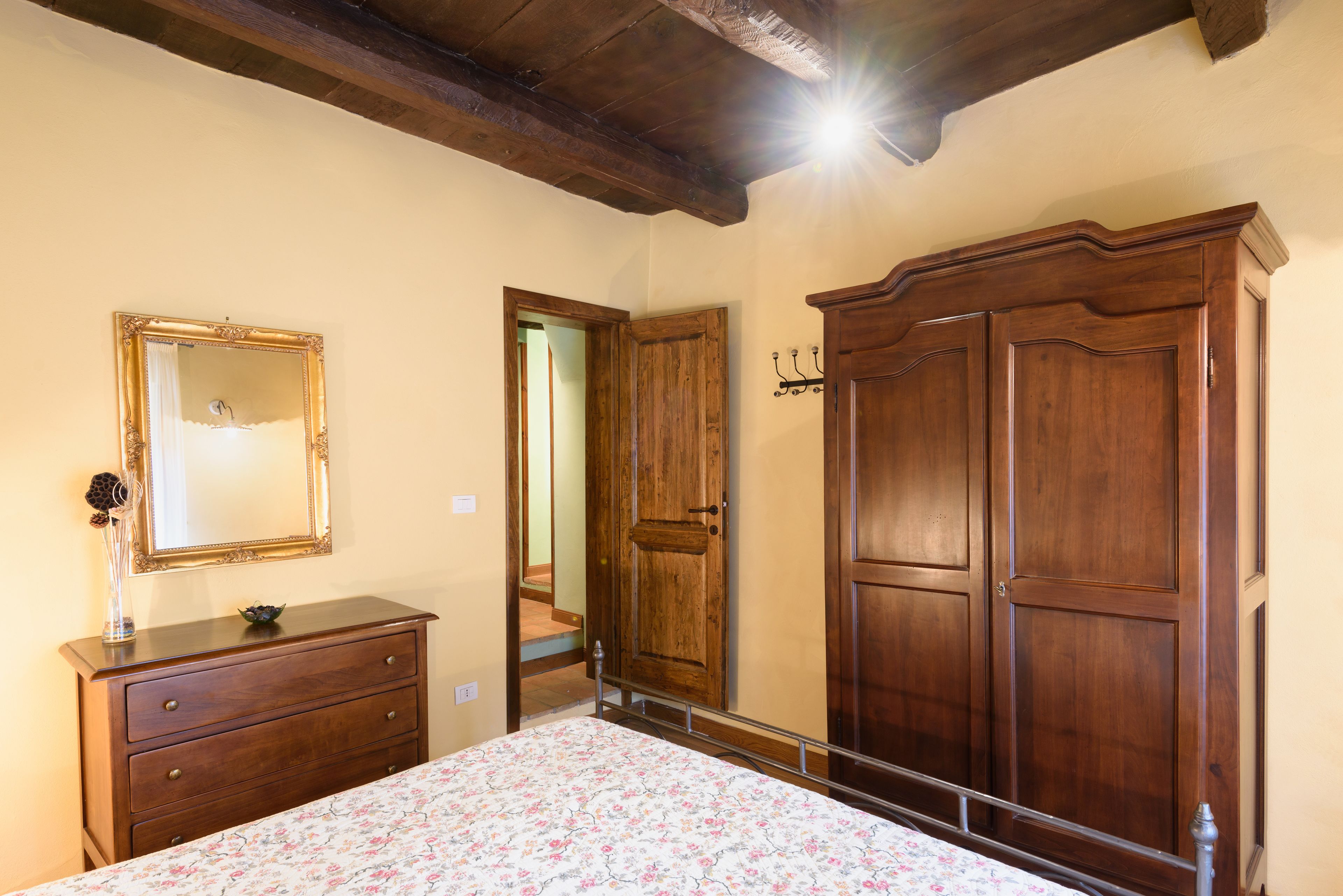 Ein Schlafzimmer mit einem Holfischschrank, einer Kommode und einem Bett mit Blumenmuster-Bettwäsche.