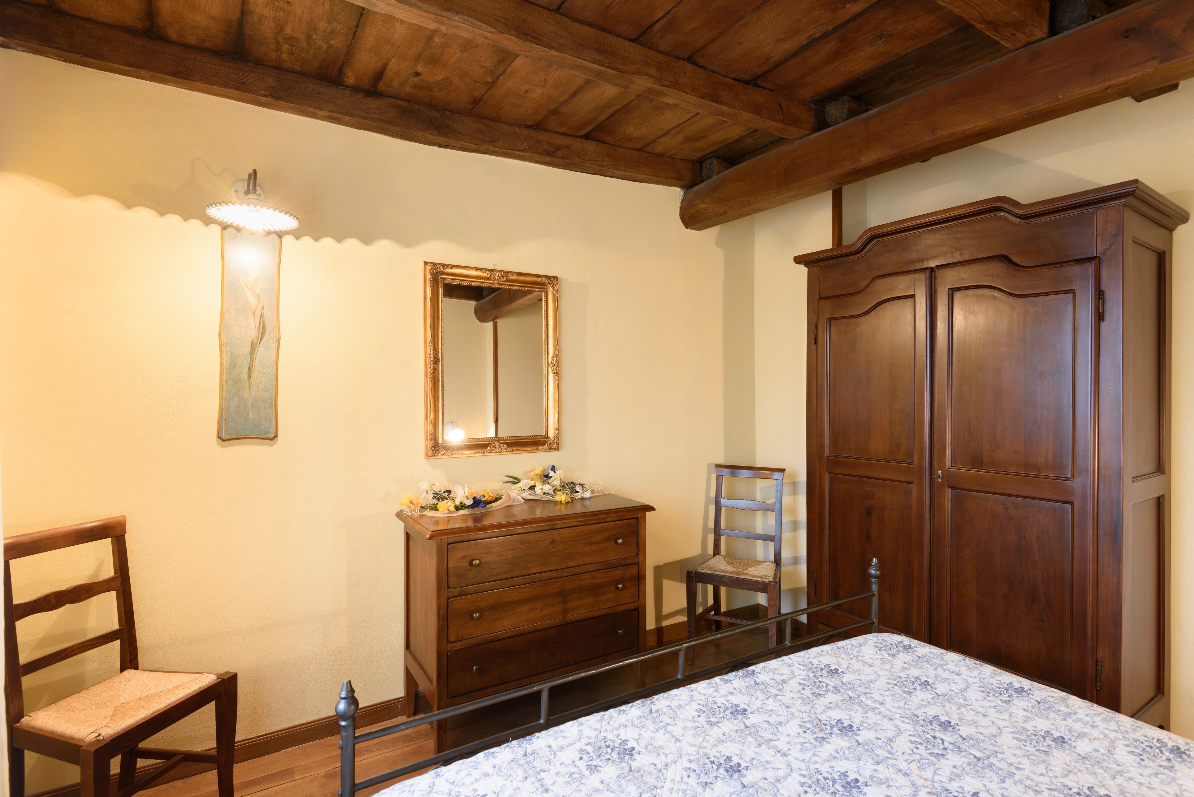Une chambre à coucher avec un lit en bois, une commode, une chaise, un miroir et une armoire.