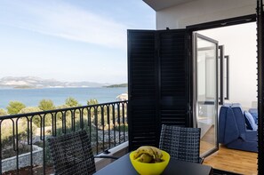 Ein Balkon mit Meerblick, ein Tisch mit einer gelben Schüssel und ein blaues Sofa.