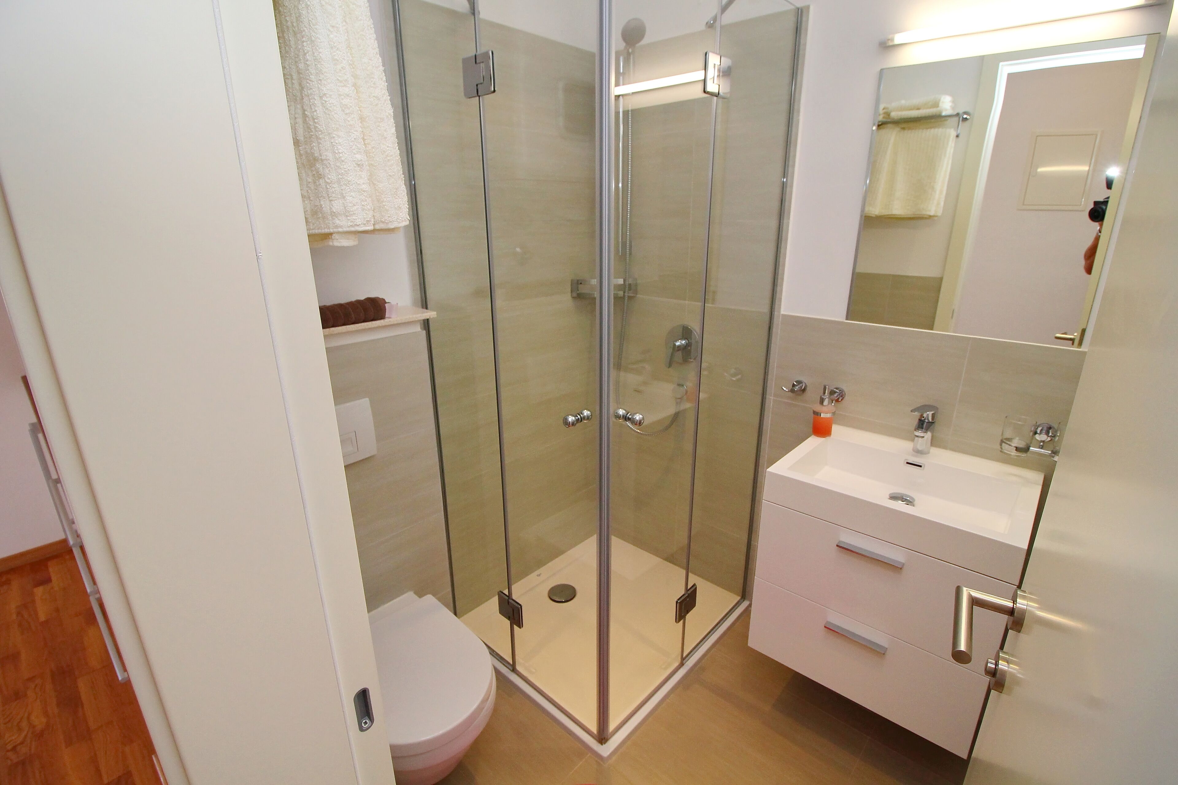 Une salle de bain moderne avec une douche à parois de verre, un lavabo blanc et des toilettes.