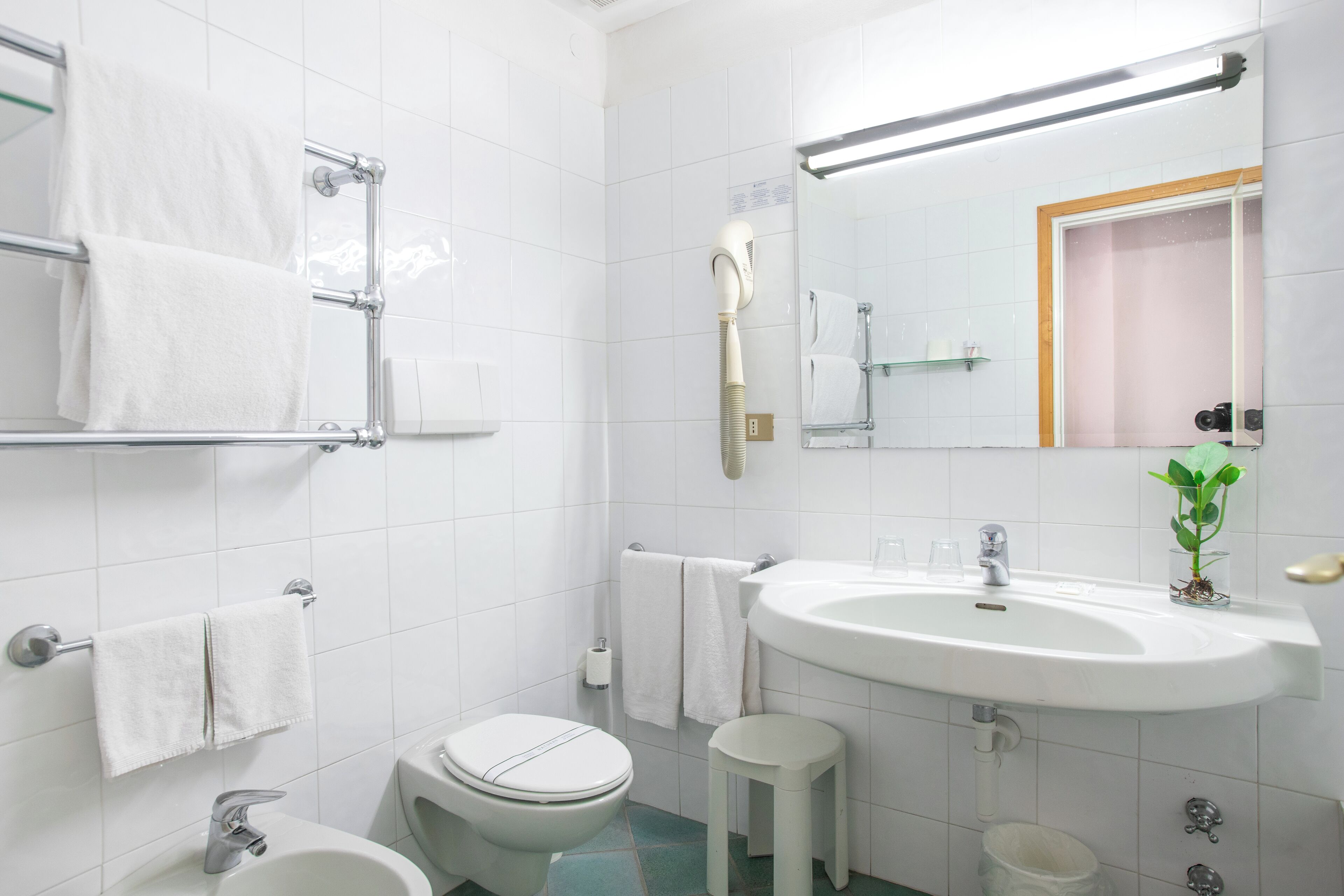 Une salle de bain moderne avec un lavabo, des toilettes et une zone de douche, le tout de couleur blanche.