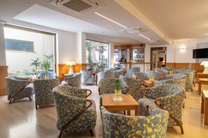 A spacious lounge area with multiple seating options, including chairs and sofas, arranged around tables. - Cav Approdo (Castiglione della Pescaia)