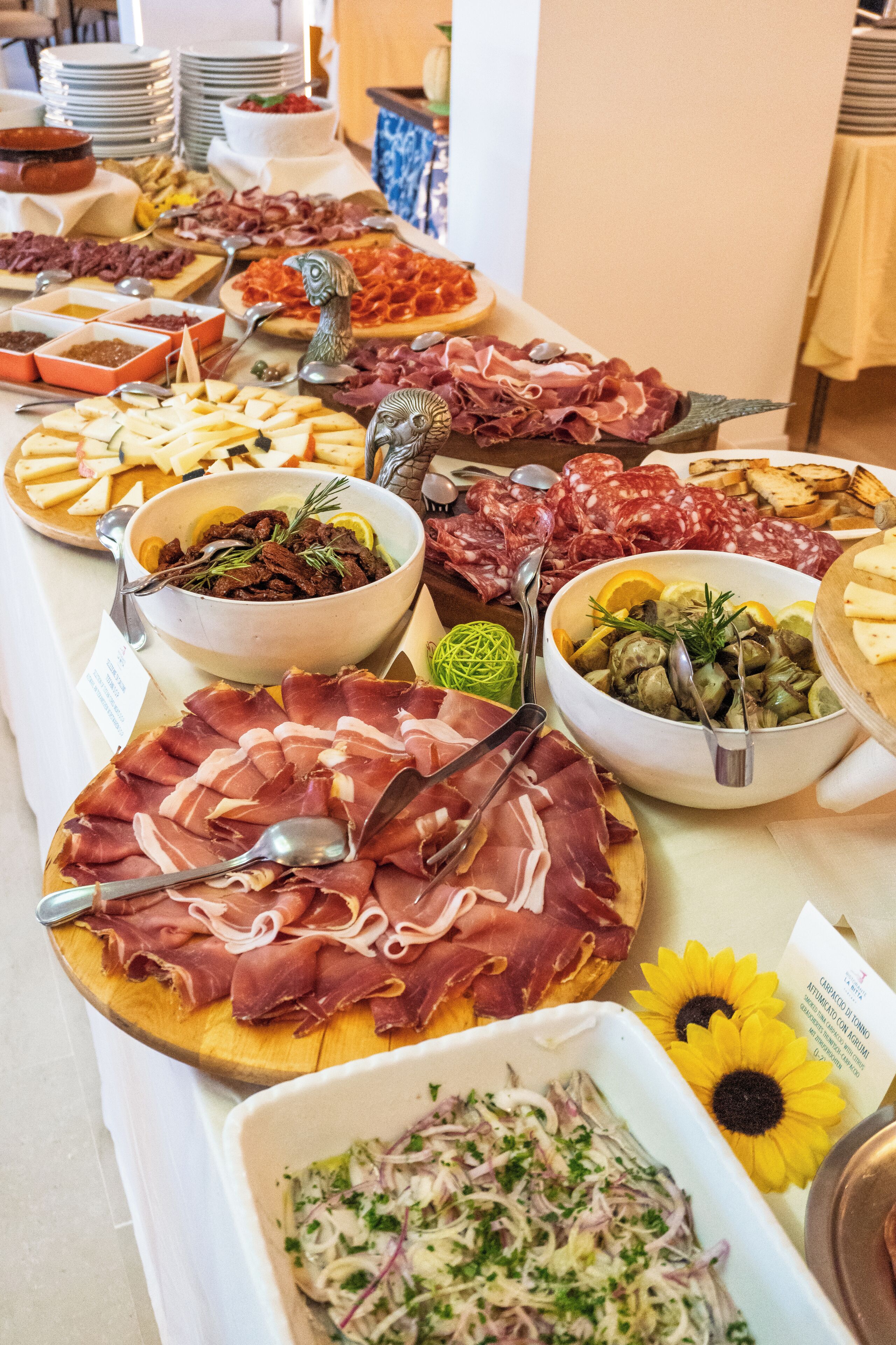A buffet with various food items including meats, cheeses, and salads.