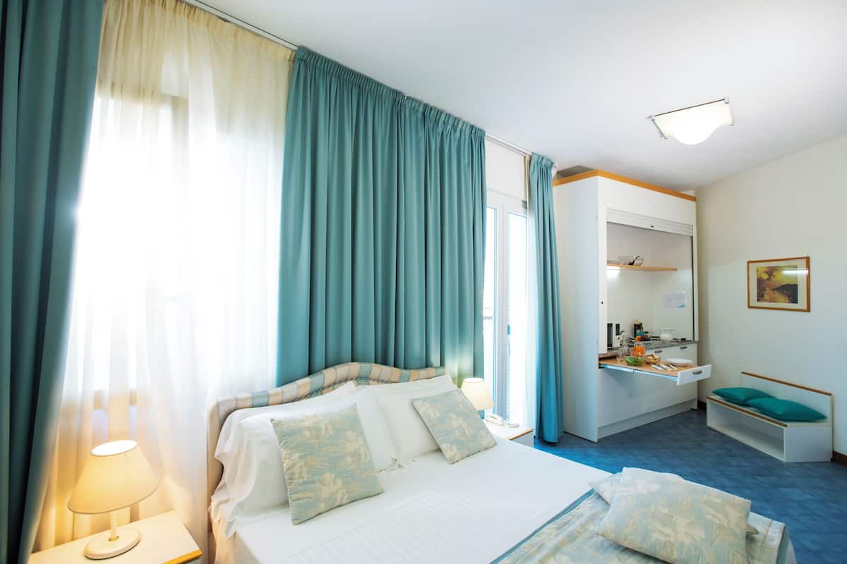 A hotel room with a bed, a desk, a chair, and a window with curtains.