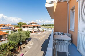 A balcony with a table and chairs, overlooking a street with buildings and a clear sky. - Cav Approdo (Castiglione della Pescaia)