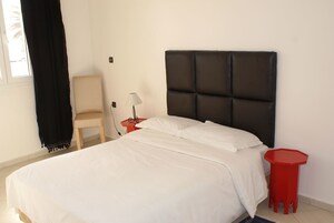 Un dormitorio con una cama, una silla, una mesita de noche y una mesita auxiliar roja.