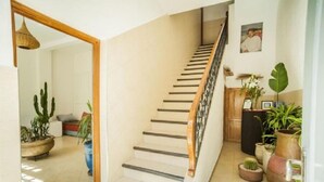 Una escalera con barandilla de madera que lleva a un rellano con un armario de madera y una foto enmarcada.