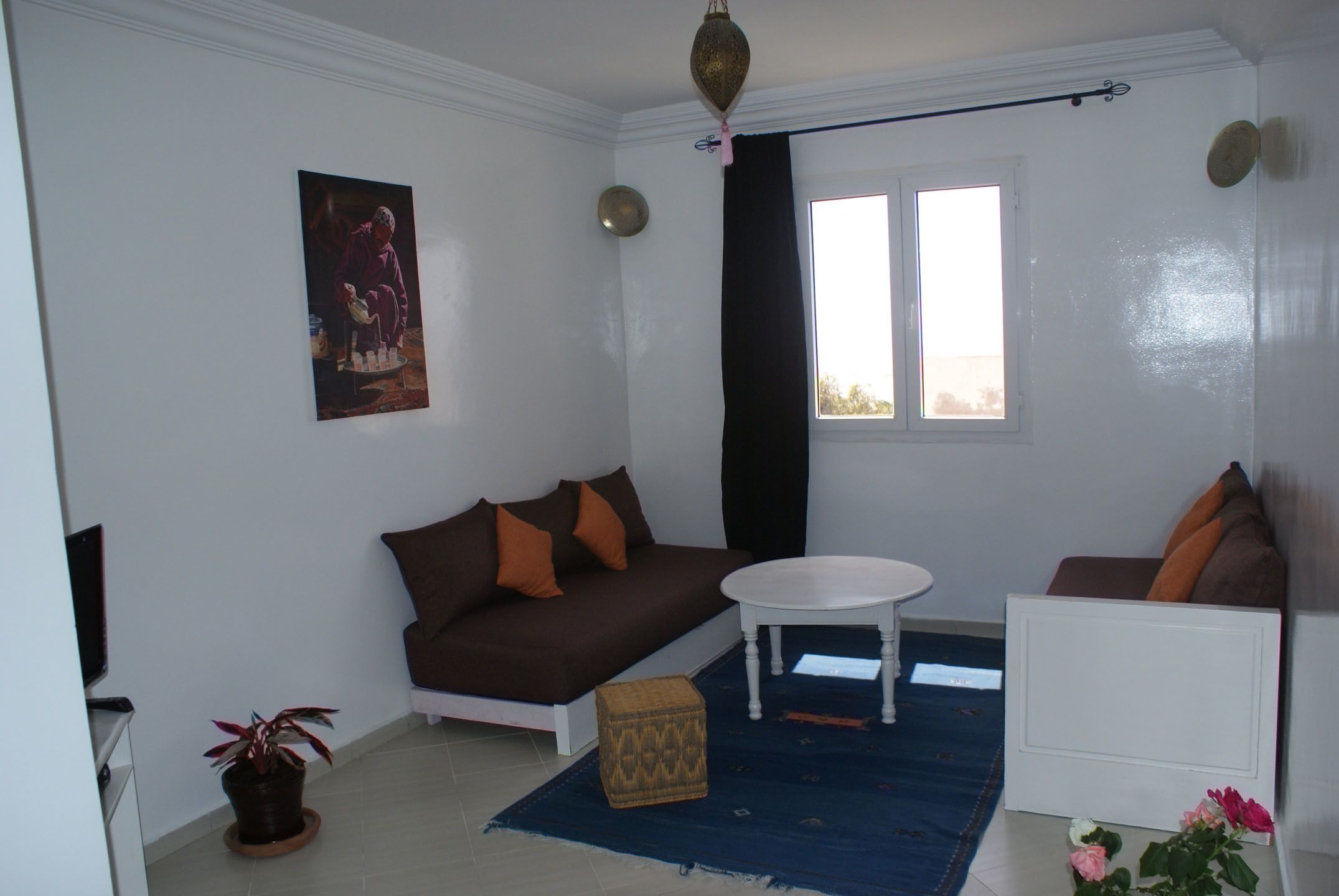 A living room with a brown sofa, a white coffee table, and a blue rug.