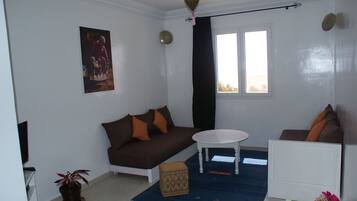 A living room with a brown sofa, a white coffee table, and a blue rug.