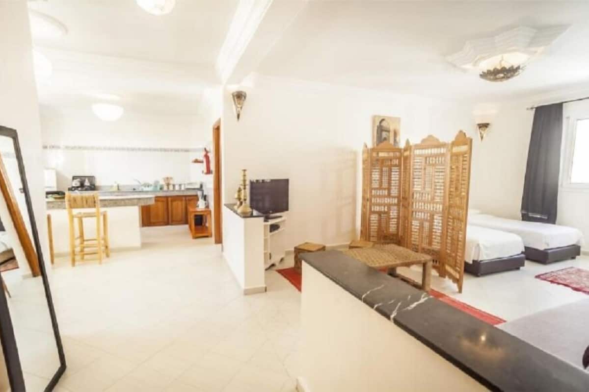 A compact hotel room with a kitchenette, a sofa bed, and a traditional wooden partition.