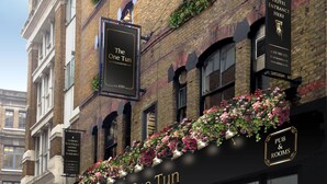 A historic building with a pub and rooms sign, a black awning, and hanging flower baskets. - The One Tun Pub and Rooms (London)