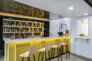 A bar area with a counter, multiple shelves of bottles, and three bar stools.