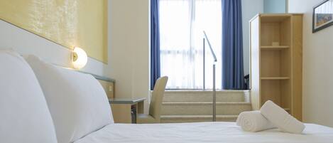 A hotel room with a bed, a desk, a chair, a staircase, and a wardrobe.