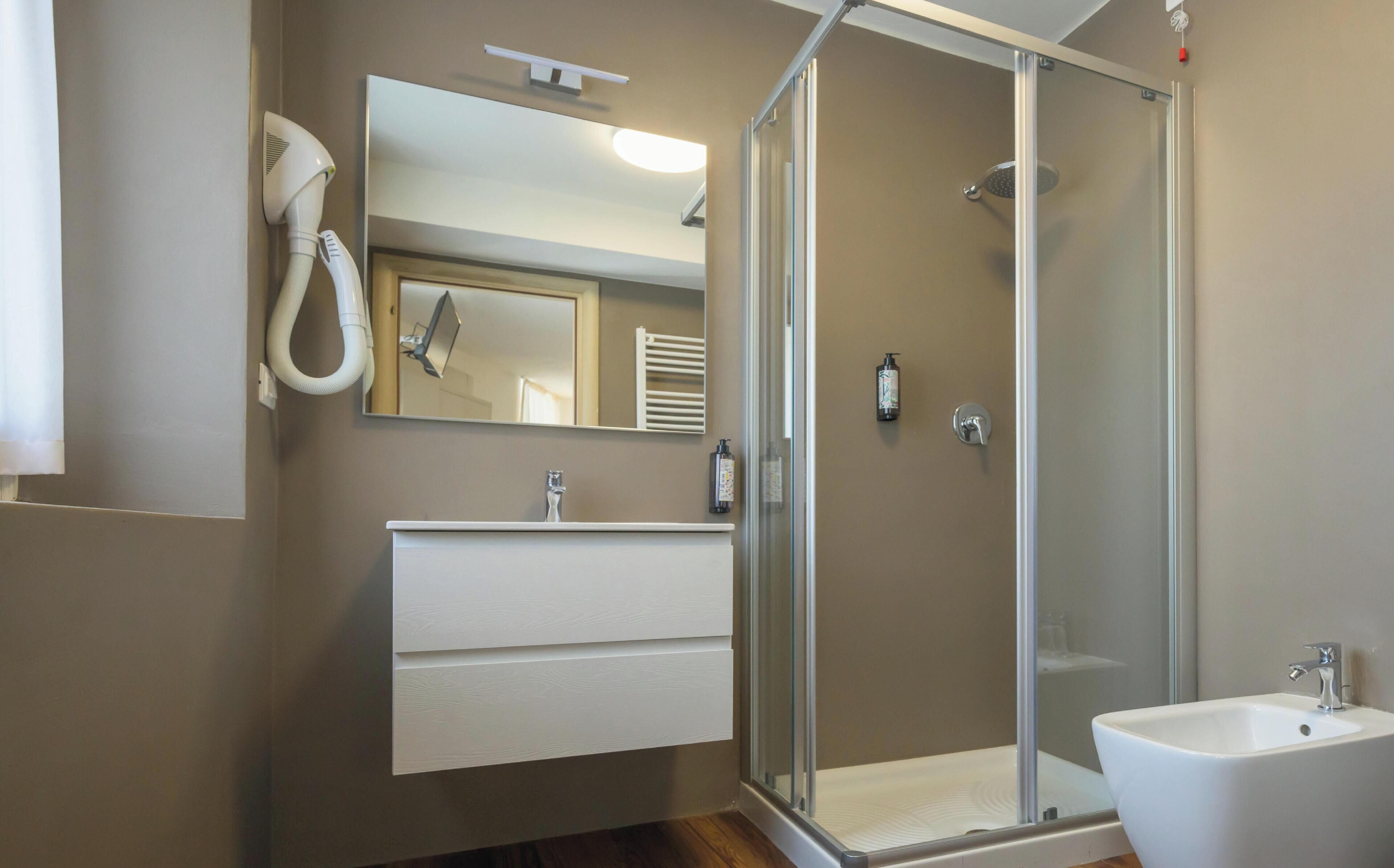 Une salle de bain moderne avec une douche à parois de verre, un lavabo blanc et un miroir au-dessus du meuble-lavabo.
