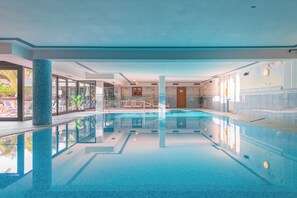 Een binnenzwembad, een buitenzwembad, parasols voor strand/zwembad