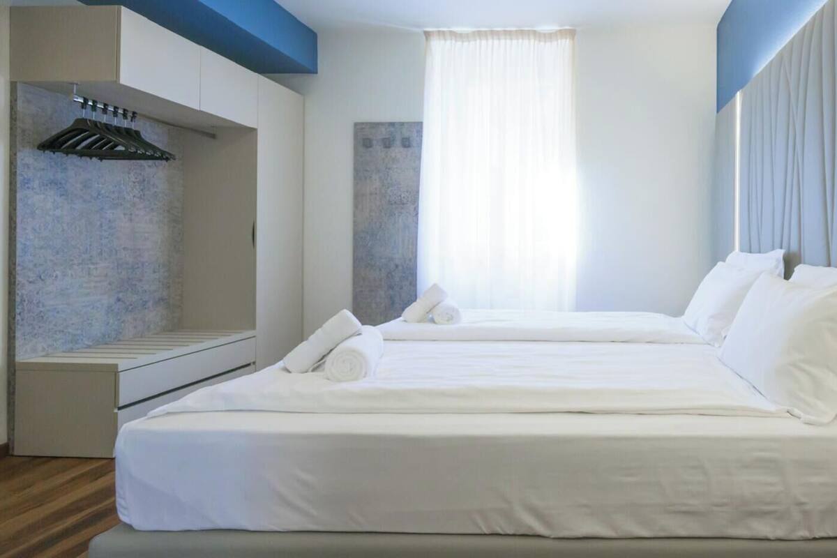 A modern hotel room with a large bed, a built-in heater, and a window with curtains.