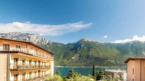 Um hotel com varanda e vista para um lago e montanhas.