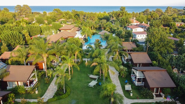 Vista aérea de un resort con varias edificaciones, una piscina y abundante vegetación.