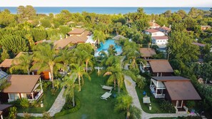 Vista aérea de un resort con varias edificaciones, una piscina y abundante vegetación.