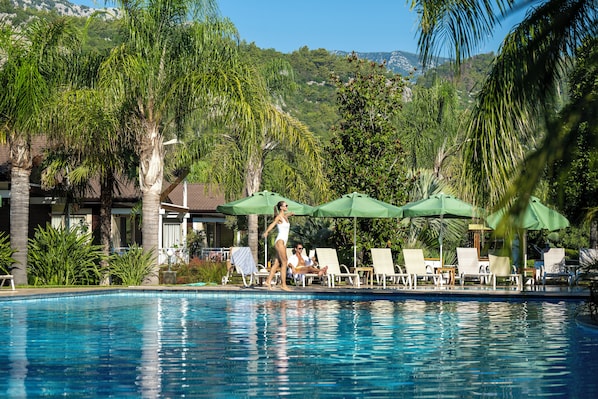 Una piscina al aire libre de temporada, sombrillas, tumbonas