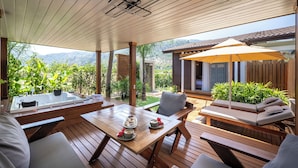 Una terraza de madera con un jacuzzi, sillas de descanso y una mesa lista para comer.