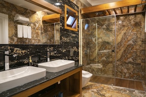 Bathroom features two sinks, a large mirror, and a glass-enclosed shower area.