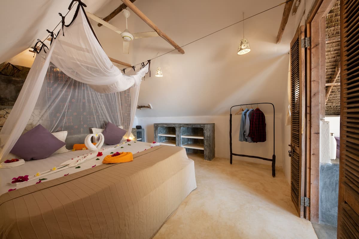 Un dormitorio con cama a dosel, mesita de noche, lámpara colgante y armario.