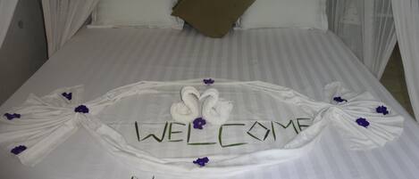 A bed with a welcome mat and the word "WELCOME" in the center, along with the word "NUR" below it.