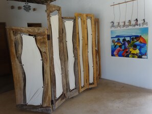 A room with a wooden structure, possibly a furniture piece, and a colorful painting on the wall. - Nur Beach Hotel (Jambiani)