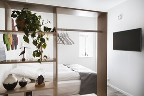 A modern bedroom with a bed, a TV, a plant, and a shelf with decorative items. - Island Apartments (Reykjavik)